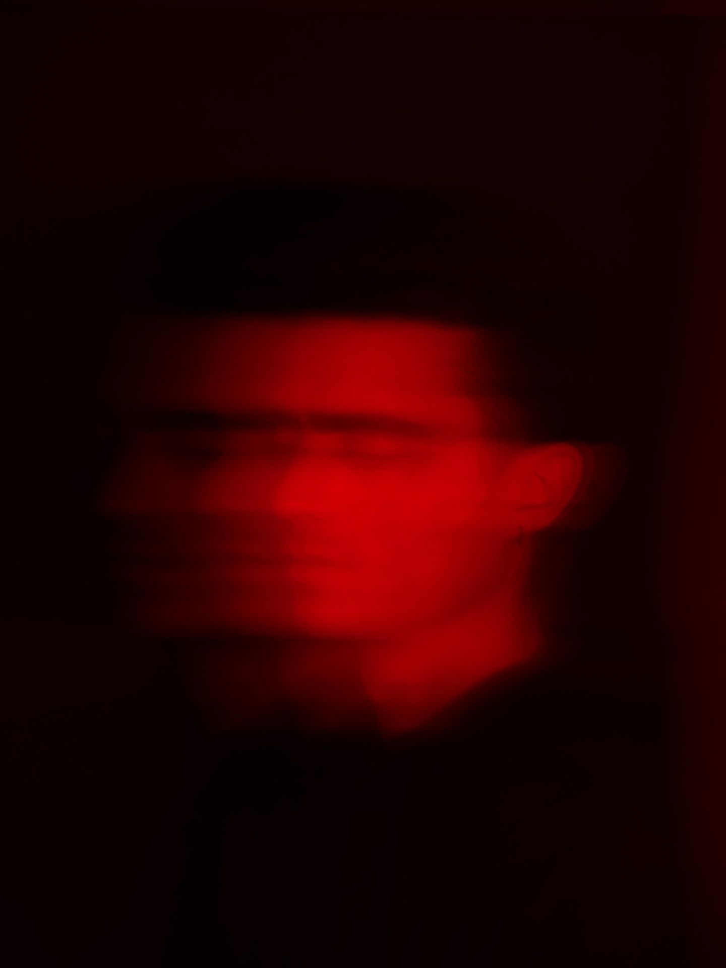 Red-lit face blurs against black background.